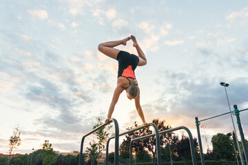 woman athlete doing handstand on parallel bars