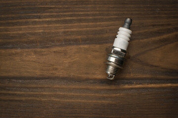 An internal combustion engine spark plug on a wooden background.