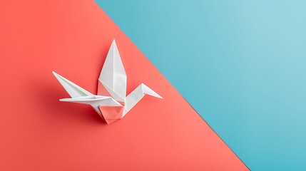 Red and white origami paper dove on blue and pink background