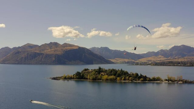 Paraglider being towed by speedboat over Lake Wanaka, New Zealand