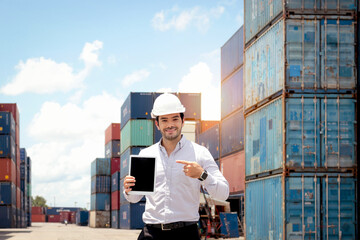 Portrait of handsome businessman with safety helmet holding and presenting digital tablet during...