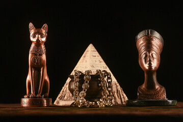 Bust of goddess Bastet and Nefertiti on the table on the dark background.Ancient Egypt concept...