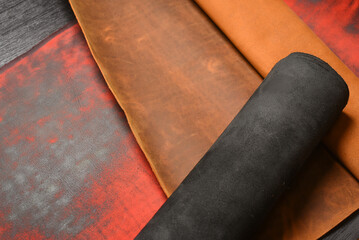 Multicolor leather rolled up pieces scrolls on the black table background. Top view.