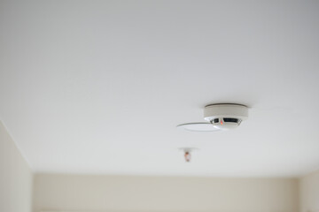White smoke detector on ceiling at home 