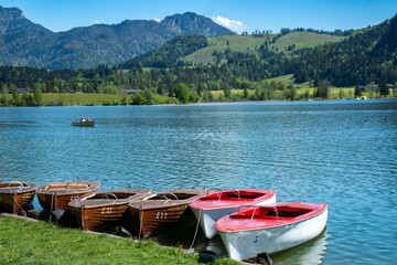 Fototapeta na wymiar Some colorful boats on the lakeshore of Walchsee, Tyrol, Austria.