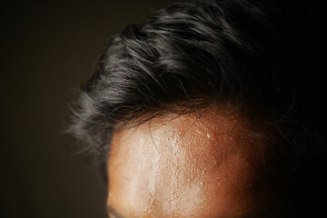 closeup of sweat on forehead against dark background ,