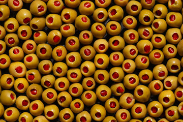 The background of juicy, salted green olives, stuffed with red peppers.