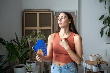 Overheated tired woman standing in room at hot summer weather day feels discomfort, suffers from...