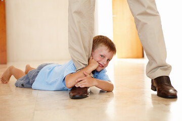 Leg, child and holding on parent in portrait, play and hanging on father for game on floor in home. Male person, kid and relax on tile or clinging for support, boy and smile for funny joke or happy