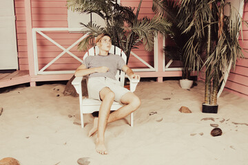 Early morning. A young attractive guy is relaxing near a bungalow.