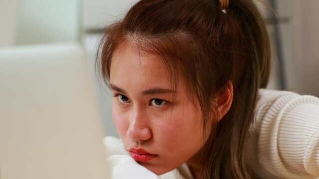 bored Tired exhausted, fatigue and fell asleep. Yaoung asian thai female working on laptop in kitchen room at home. Overwork. Exhausted woman  sleeply eye at workplace