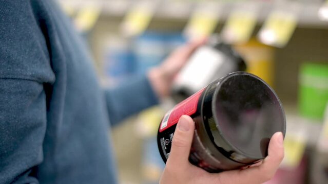 Woman choose sport nutrition in specialty store. Vitamins, protein, dietary supplements and other substances for health of athletes and ordinary people. Sports wellnes.