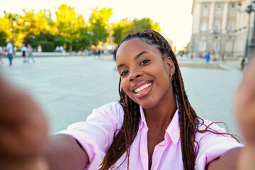 Cuban young woman smiling and doing a selfie while sightseeing in Madrid, Spain.