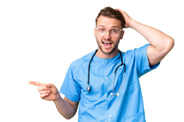 Young nurse man over isolated chroma key background surprised and pointing finger to the side