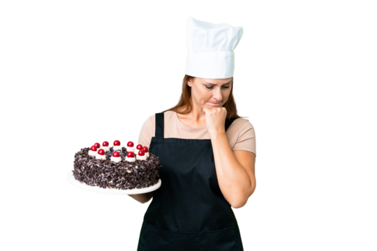 Middle age pastry chef woman holding a big cake over isolated background having doubts
