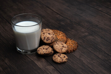 Comida. Vaso de leche con galleta, sobre mesa de madera, primer plano.