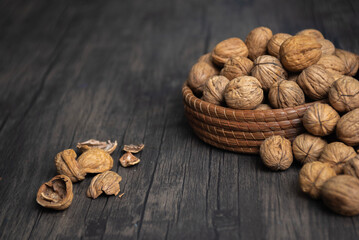 Comida. Canasta llena de nueces tanto que se desbordan, con cascaras rotas sobre la mesa. Plano...