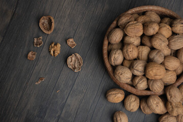 Comida. Canasta llena de nueces tanto que se desbordan, con cascaras rotas sobre la mesa. Plano cenital