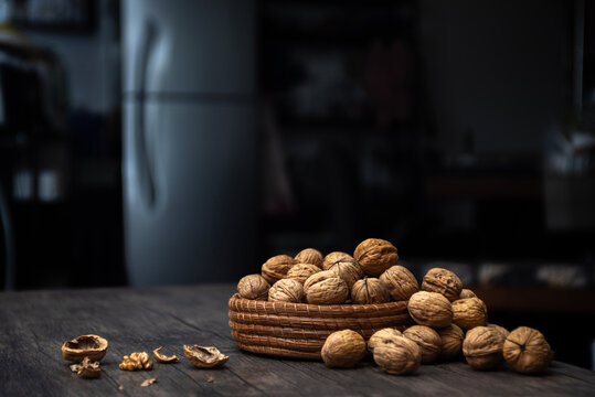 Comida. Canasta llena de nueces tanto que se desbordan, con cascaras rotas sobre la mesa. Plano cerrado.