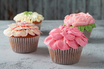 Colorful cupcakes with flower shaped decorations made with buttercream frosting.
