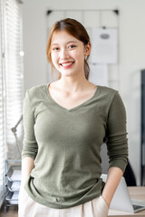 Portrait of young smiling woman looking at camera. Happy girl standing in creative office.