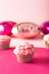 Colorful cupcakes on vibrant colored paper background. Decoration shaped like flowers with buttercream frosting.