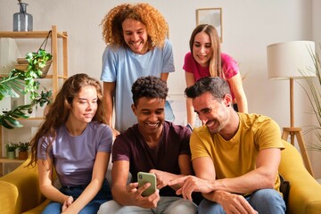 Group of young teenagers watching something funny on mobile screen at home.