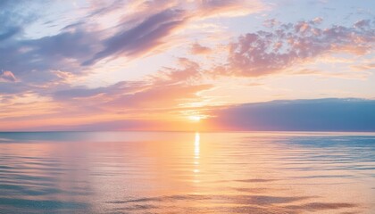 Fototapeta premium Serene sunset over calm ocean waters, with soft clouds reflecting warm hues