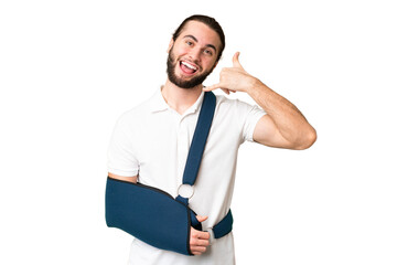 Young handsome man with broken arm and wearing a sling over isolated chroma key background making...