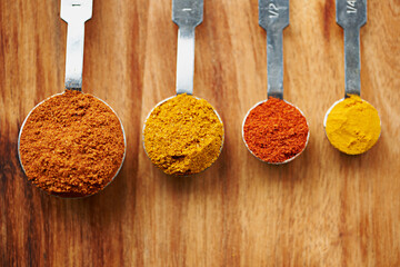 Spoons, spice and selection to measure for seasoning on kitchen table, turmeric and paprika for...