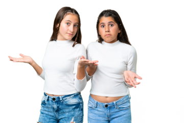 Friends girls holding gift and a birthday cake over isolated chroma key background having doubts while raising hands and shoulders