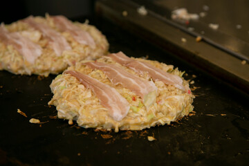Okonomiyaki is a savory Japanese cabbage pancake “grilled as you like it“ with your choice of protein and tasty condiments and toppings.