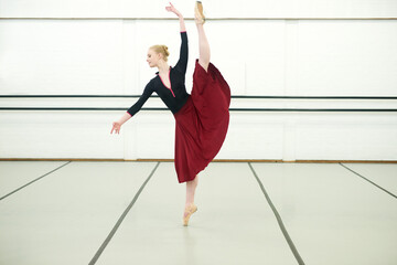 Woman, ballet and dancing in studio for fitness, exercise and training for performance or show. Young female ballerina, rehearsal and elegant indoor at school of art for creative, artist and barre