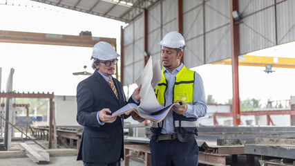 Two civil engineers checking information from file and tablet for quality control in a precast or...
