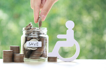 Man on wheelchair and coin money in the glass bottle on natural green background,Save money for...