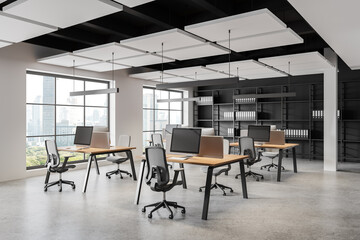 Modern coworking interior with pc monitors on desks, panoramic window