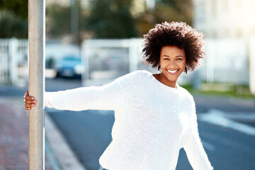 Happy, black woman and pole in city for portrait with white sweater with fun, carefree and relax by...