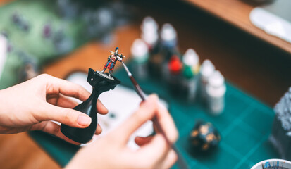 Hand using brush paint acrylic colour to miniatures for tabletop role playing game or board games