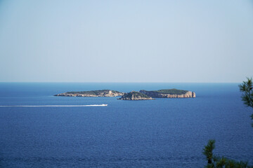 A white coast guard boat is sailing in the Mediterranean Sea against the backdrop of three islands...