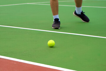 Fototapeta premium Close up of tennis player legs with black shoe playing on tennis court. Tennis player in the outdoor court