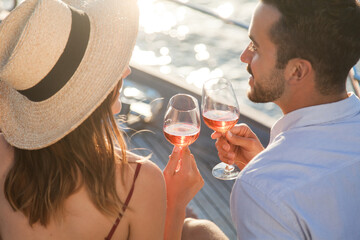Drinking wine on yacht at sea. Romantic traveling at sunset. Happy couple in love with wineglasses...