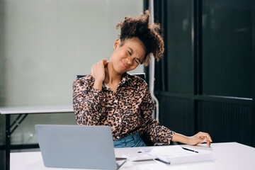 Overworked young businesswoman office worker suffering from neck pain after had a long day at her...