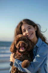 Smiling Young Woman Hugging Her Brown Poodle by the Sea