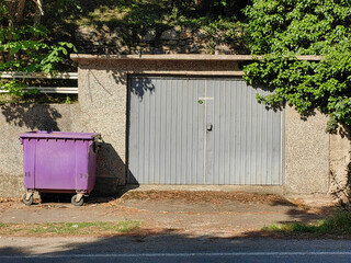 Sunlit Elegance. Gray Garage Door and Purple Garbage Bin.