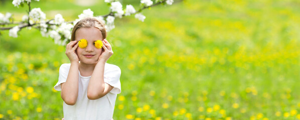 World Dandelion Day. Child girl closes her eyes with dandelions against a flowering field. banner. 