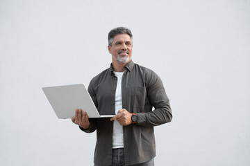 Mature 40s Indian happy man using wireless pc for business solutions, isolated on white background....