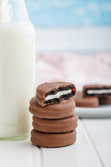 Chocolate Covered Cookies and Glass of Milk on white table.