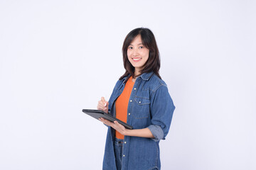 Asian woman wearing orange shirt and denim jean jacket is holding a tablet and a stylus against a...