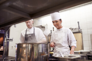 Chef, teamwork and cooking in professional kitchen at stove top or fine dining cuisine, hospitality or service. Man, woman an hat as restaurant career or food preparation or dinner rush, meal or help