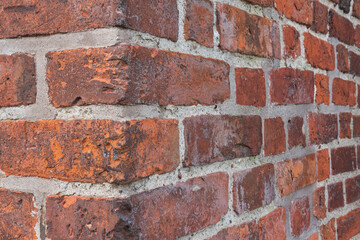 Close-up of the corner of an ancient red brick building. There are chips and cracks. Background....
